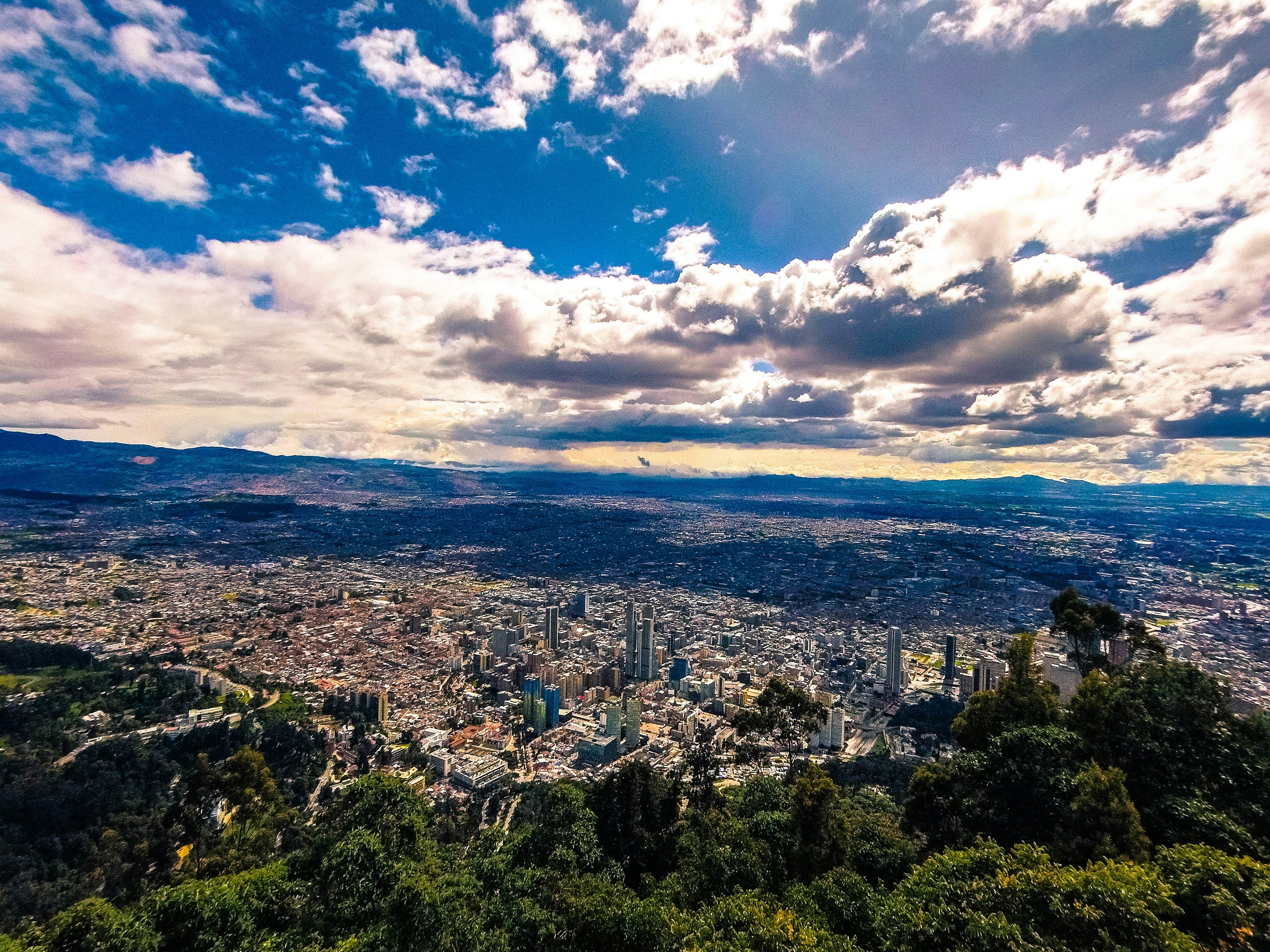 Bogotá seen from Monserrate — the vast city stretching across the Andean plateau under a bright sky of towering cumulus clouds.