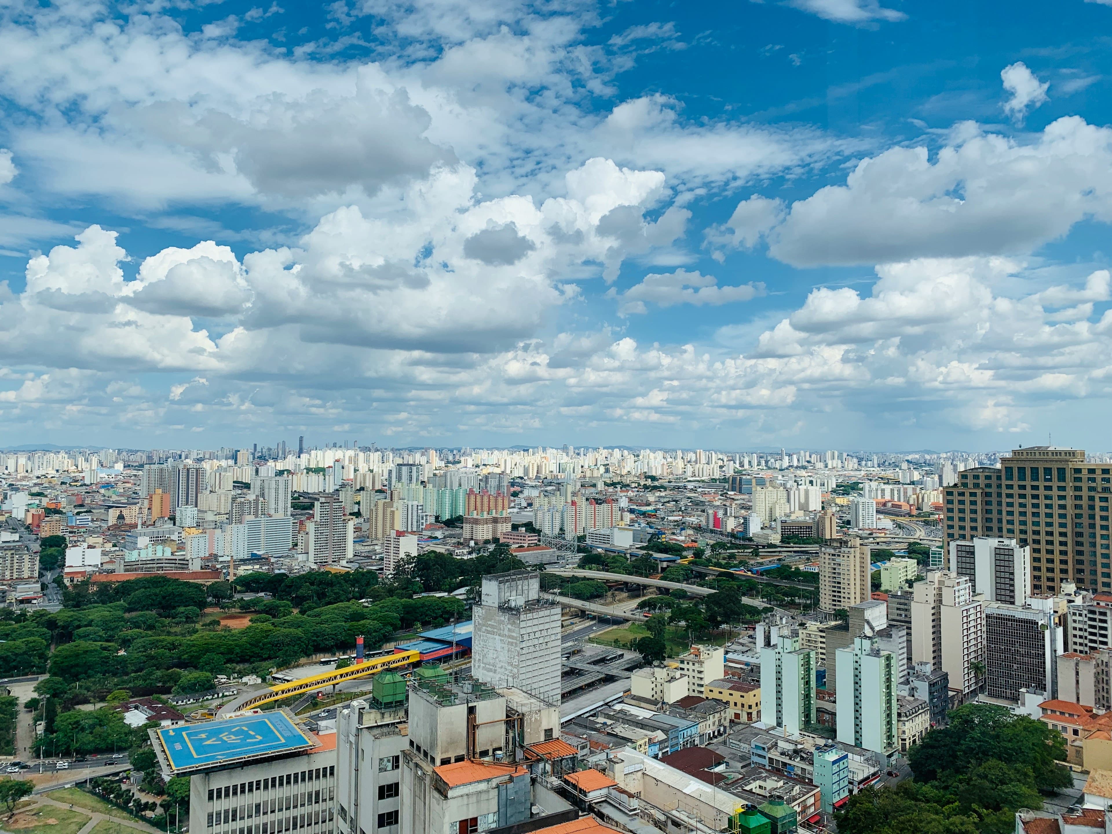 São Paulo's skyline — an endless expanse of high-rise towers stretching to the horizon under a bright, cloud-dappled blue sky.