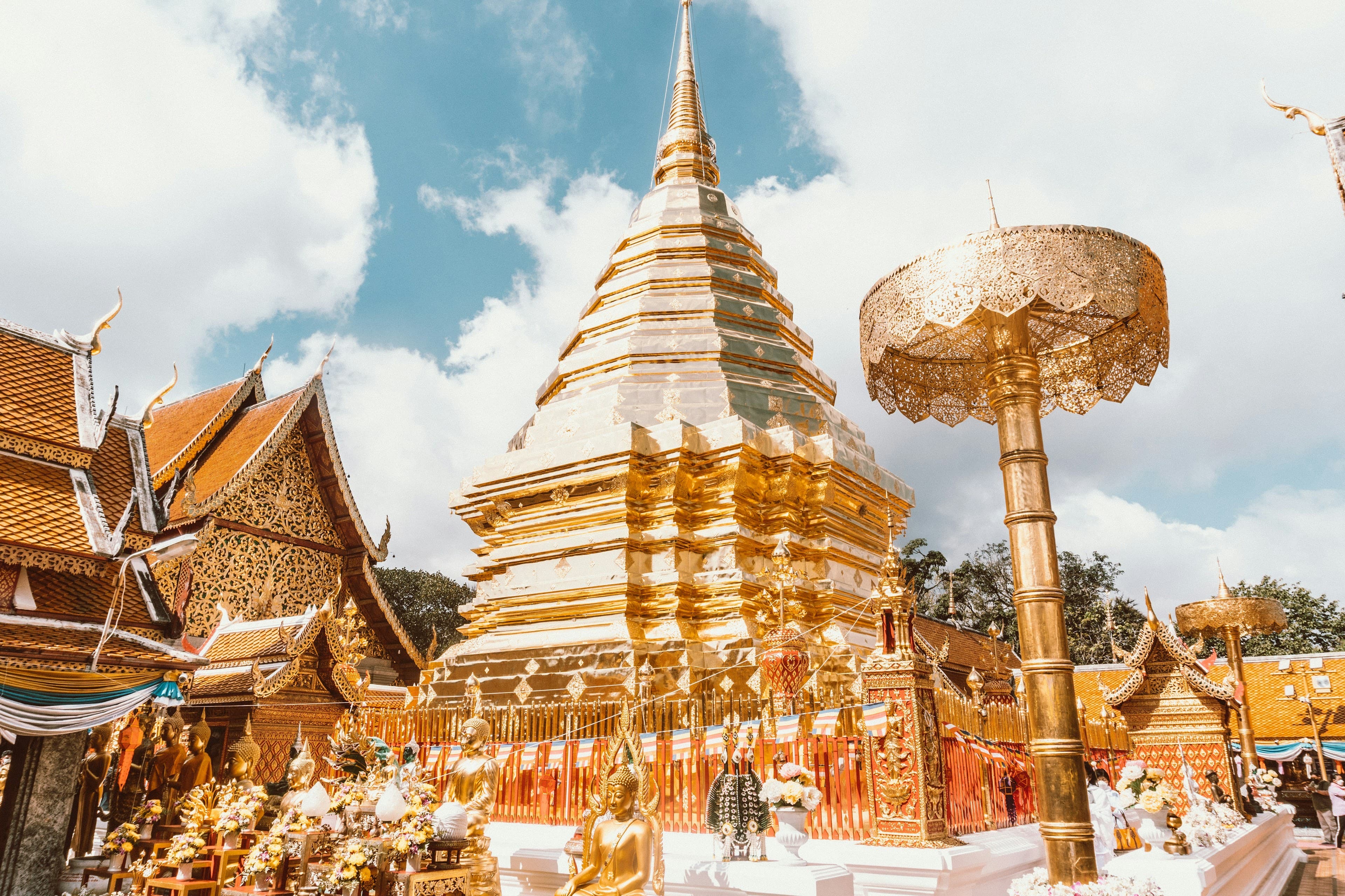 The golden chedi of Wat Phra That Doi Suthep in Chiang Mai, ringed by golden umbrellas and ornate Lanna temple buildings.