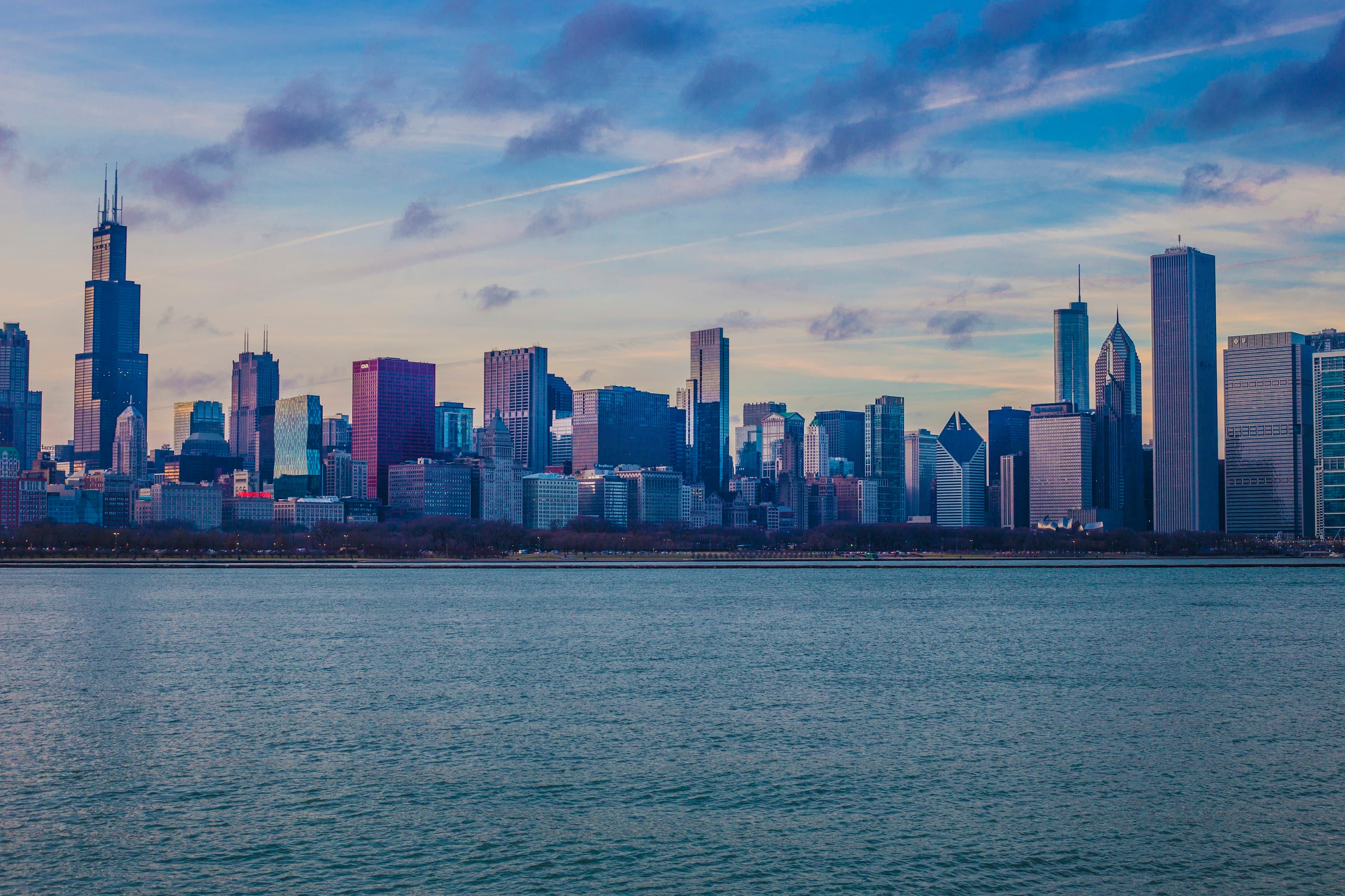 The Chicago skyline across Lake Michigan at dusk, the Willis Tower rising over downtown beneath a dramatic sky.